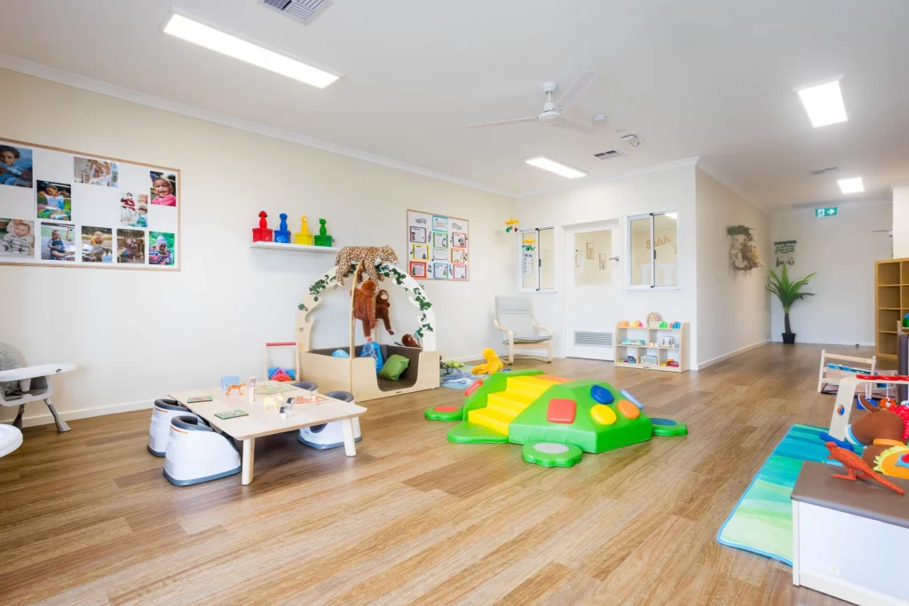 A vibrant and spacious indoor play area at Buttercups Perth Childcare featuring a colourful climbing turtle toy, activity tables, soft toys, and educational displays, designed for children’s exploration and development.