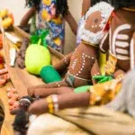 A close-up of handcrafted Indigenous dolls adorned with traditional artwork and patterns, displayed alongside colourful fabric vegetables and cultural items on a wooden tray at Buttercups Perth Childcare, celebrating diversity and cultural appreciation.