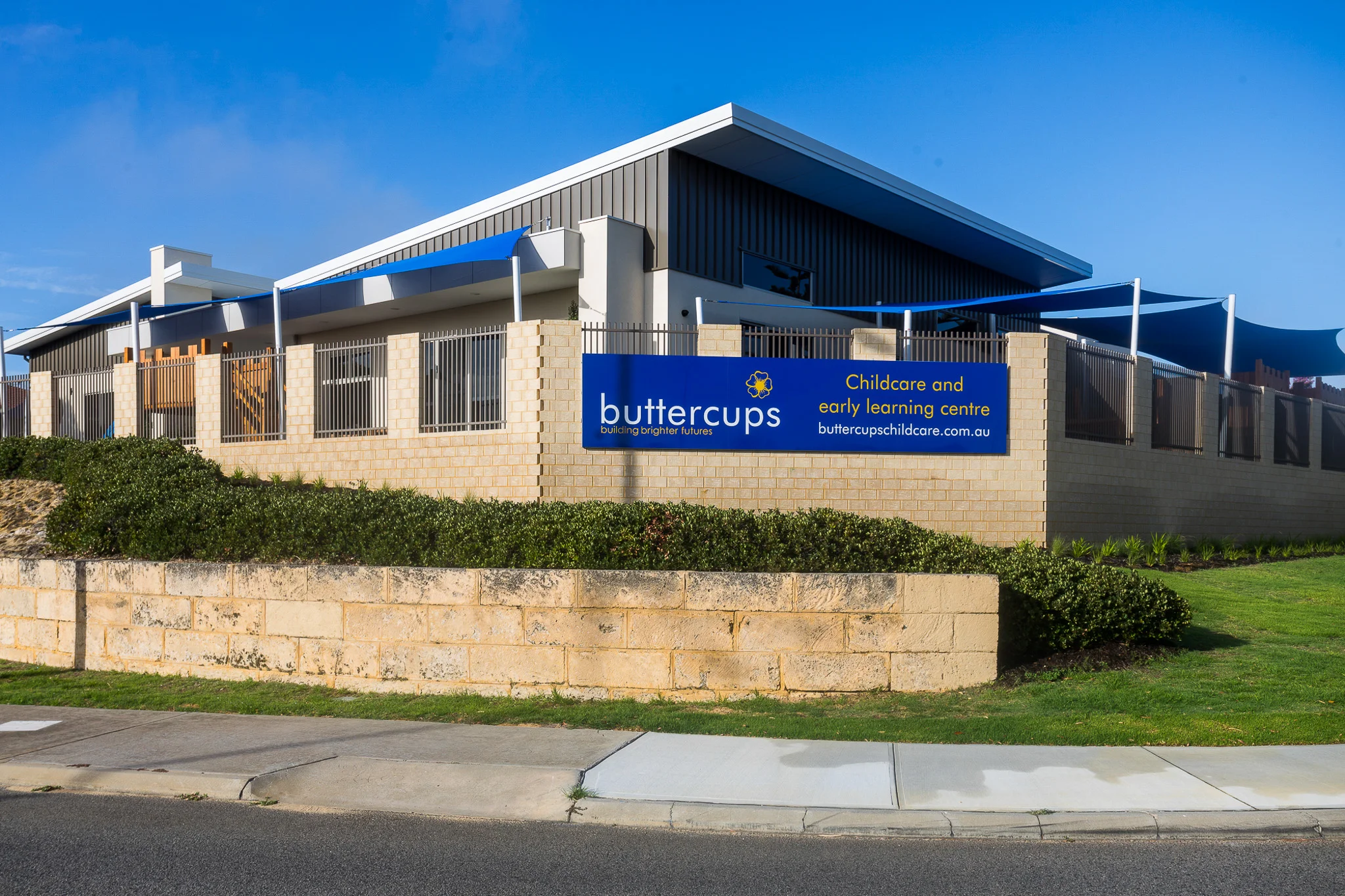 Exterior view of Buttercups Perth Childcare and Early Learning Centre, showcasing a modern, secure facility with clear signage, shaded outdoor play areas, and a welcoming environment designed to support children's growth and development.