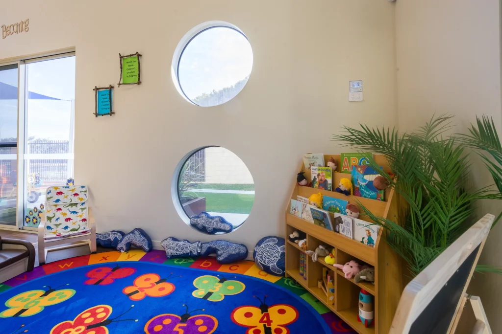 Cosy reading corner at Buttercups Perth Childcare, featuring a colourful rug, inviting book display, and comfy cushions, creating a warm and engaging space for children to explore stories and spark their imagination.