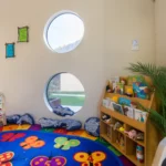 Cosy reading corner at Buttercups Perth Childcare, featuring a colourful rug, inviting book display, and comfy cushions, creating a warm and engaging space for children to explore stories and spark their imagination.