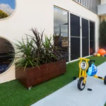 Outdoor play space at Buttercups Perth Childcare featuring a bike track, vibrant play equipment, and lush greenery, designed to encourage active exploration and imaginative play in a safe and engaging environment.