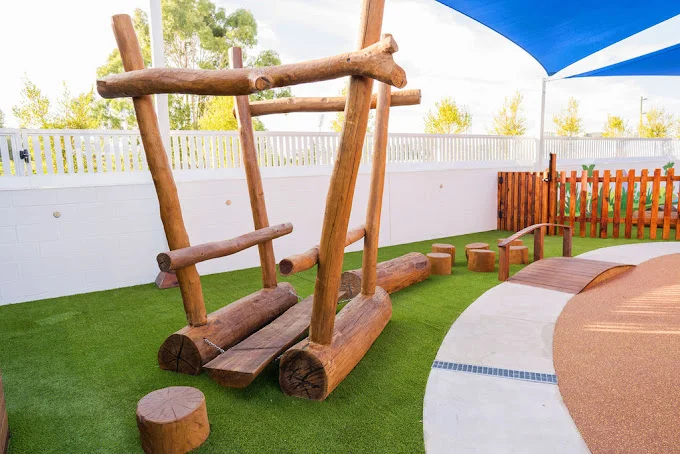 The image shows a wooden playground structure at Buttercups Perth Childcare, designed for outdoor play and exploration.