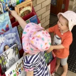 Two young children at Buttercups Perth Childcare exploring a vibrant book display, filled with colourful and engaging children’s books, fostering a love for reading and discovery.