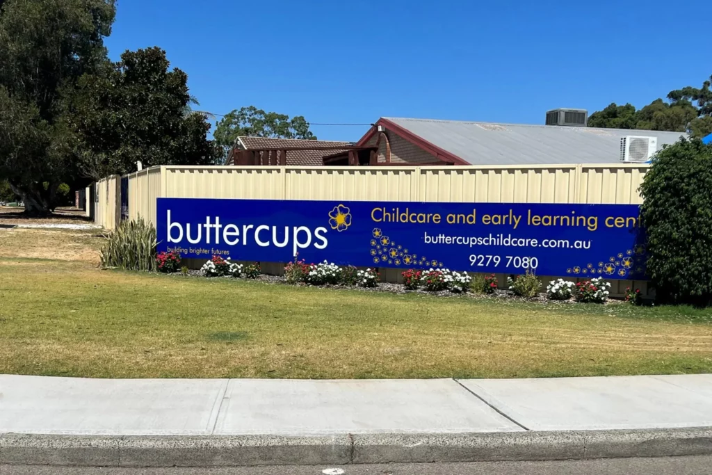 The Buttercups Perth Childcare and Early Learning Centre sign prominently displayed on a colourful lawn with blooming flowers, showcasing the centre’s commitment to building brighter futures.