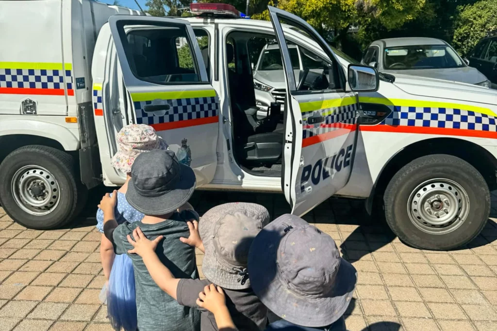 Children from Buttercups Perth Childcare excitedly explore a police vehicle during a special community visit, fostering curiosity and awareness of local safety services.