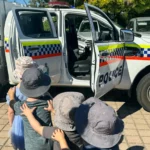 Children from Buttercups Perth Childcare excitedly explore a police vehicle during a special community visit, fostering curiosity and awareness of local safety services.