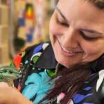 Smiling educator at Buttercups Perth Childcare gently holding a green tree frog, highlighting nature-based learning and hands-on experiences.