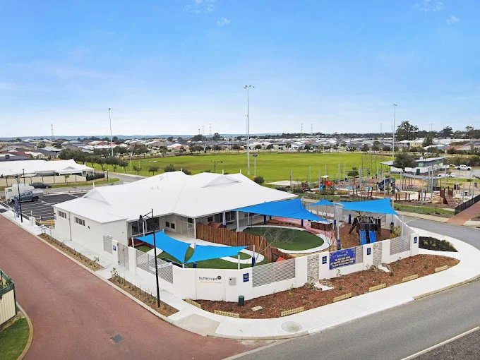 Aerial view of Buttercups Perth Childcare showcasing its modern building design, secure outdoor play areas with shade sails, and surrounding neighbourhood amenities.