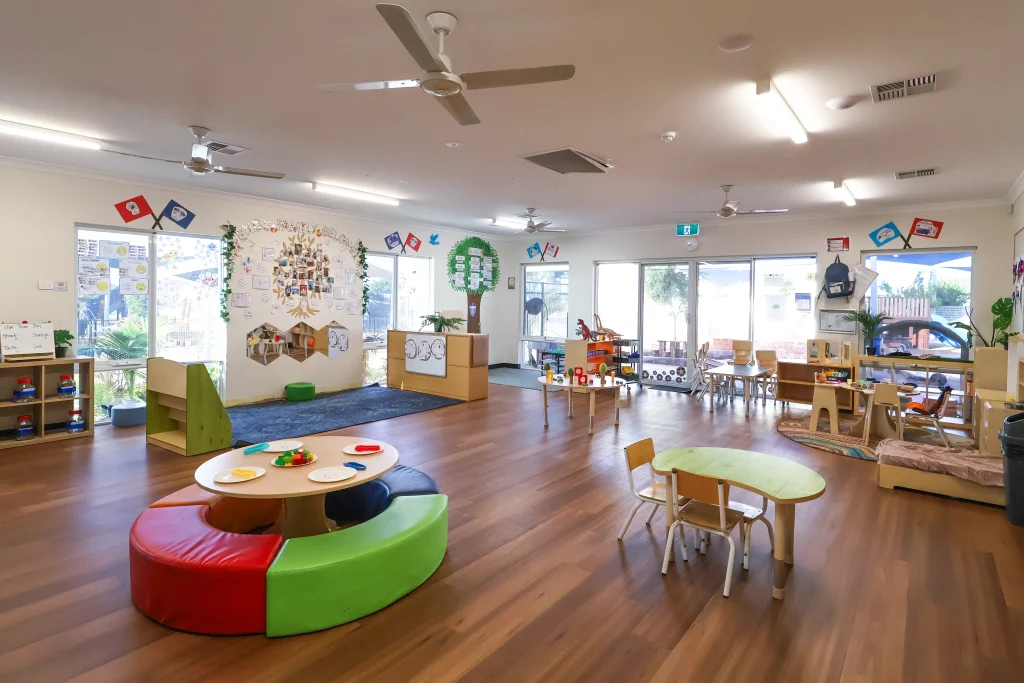 The vibrant indoor learning space at Buttercups Perth Childcare features interactive play areas, engaging wall displays, and child-sized furniture designed to foster creativity and collaboration. Large windows fill the room with natural light, creating an inviting and stimulating environment for early learning.