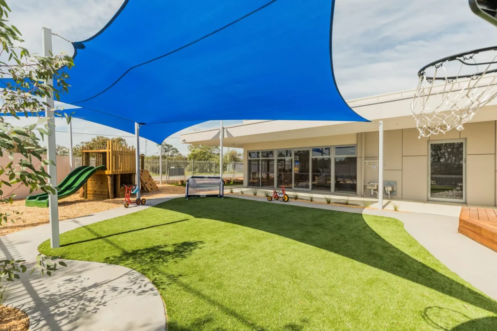 Outdoor play area at a Perth childcare centre, featuring shaded spaces, a slide, and open grass for safe and active play.