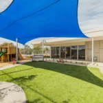 Outdoor play area at a Perth childcare centre, featuring shaded spaces, a slide, and open grass for safe and active play.