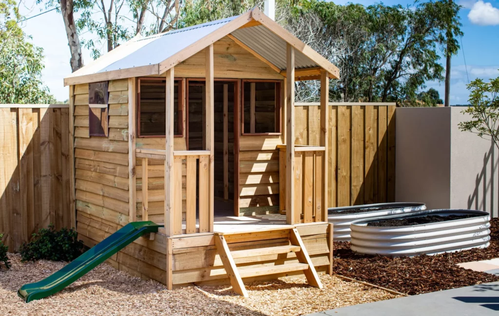 Wooden cubby house with a slide at a Perth childcare centre, offering children a space for imaginative play and outdoor fun.