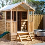 Wooden cubby house with a slide at a Perth childcare centre, offering children a space for imaginative play and outdoor fun.