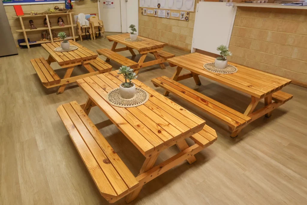 Wooden tables adorned with plants, creating a welcoming eating area at Buttercups Perth Childcare.