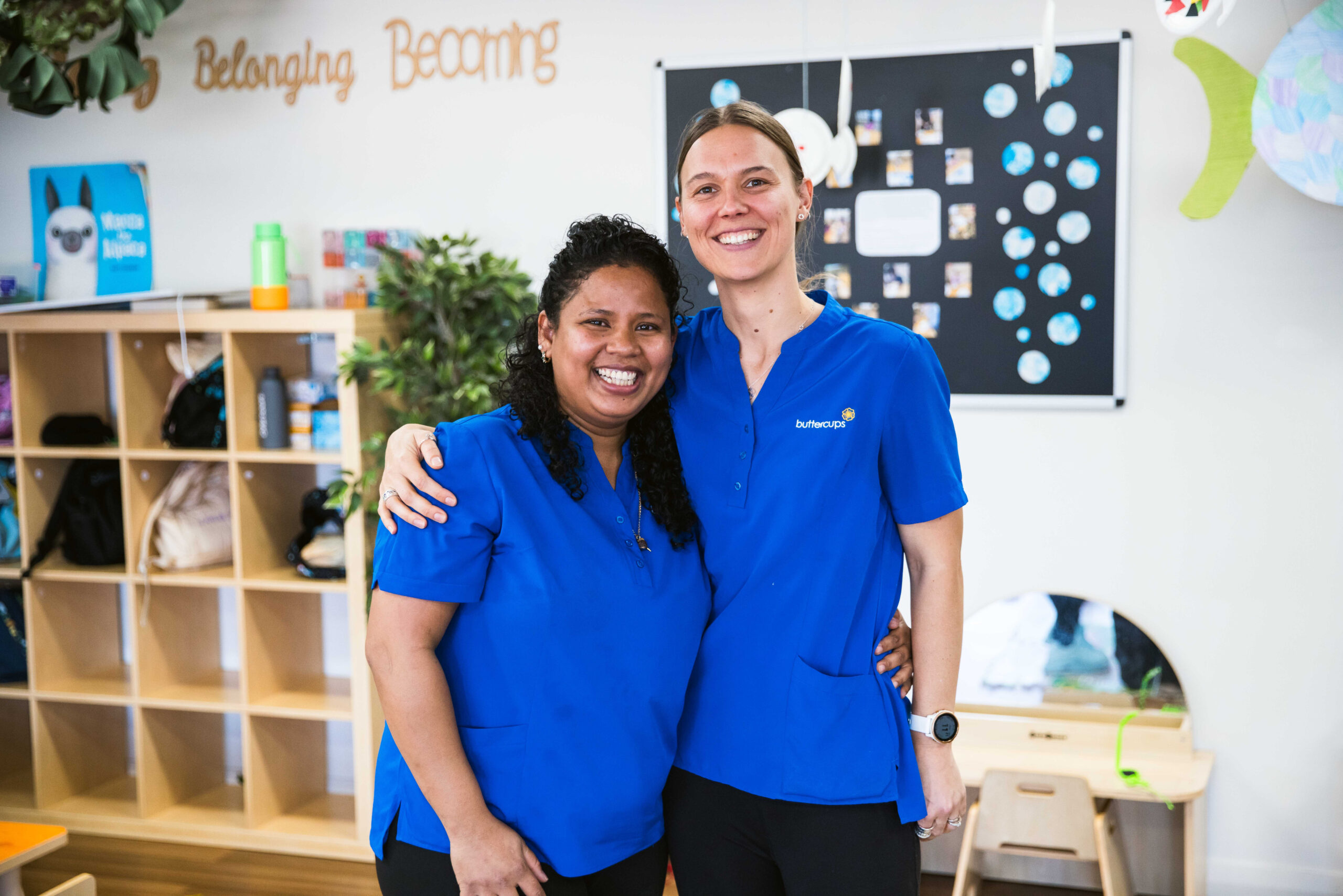 Educators from Buttercups Perth Childcare, dressed in their signature blue shirts, sharing bright, happy smiles with the camera.