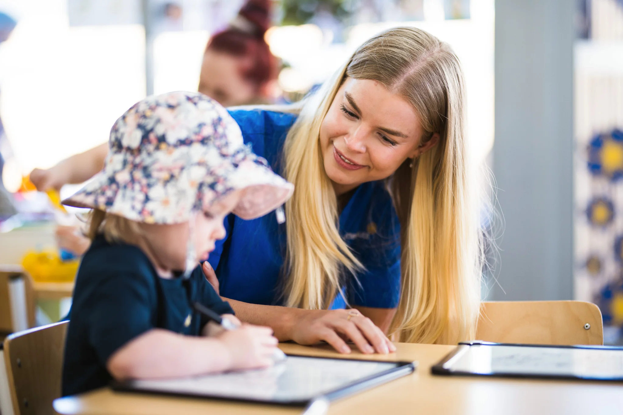 Educator encouraging a toddler during a drawing activity at a Perth daycare, nurturing creativity and early development in a warm and caring setting.