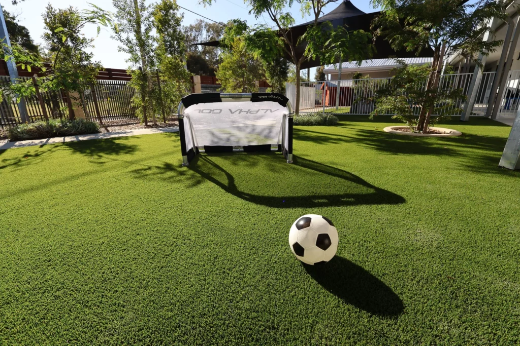 Outdoor play area at Buttercups Perth Childcare with lush artificial grass, a small soccer goal, and ball, encouraging active play and teamwork.