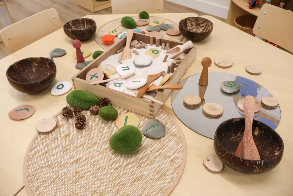 Natural play-based learning setup at Buttercups Perth Childcare, featuring wooden and stone sensory materials, alphabet stones, and tactile elements designed to encourage creativity, fine motor skills, and early literacy exploration.