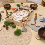 Natural play-based learning setup at Buttercups Perth Childcare, featuring wooden and stone sensory materials, alphabet stones, and tactile elements designed to encourage creativity, fine motor skills, and early literacy exploration.