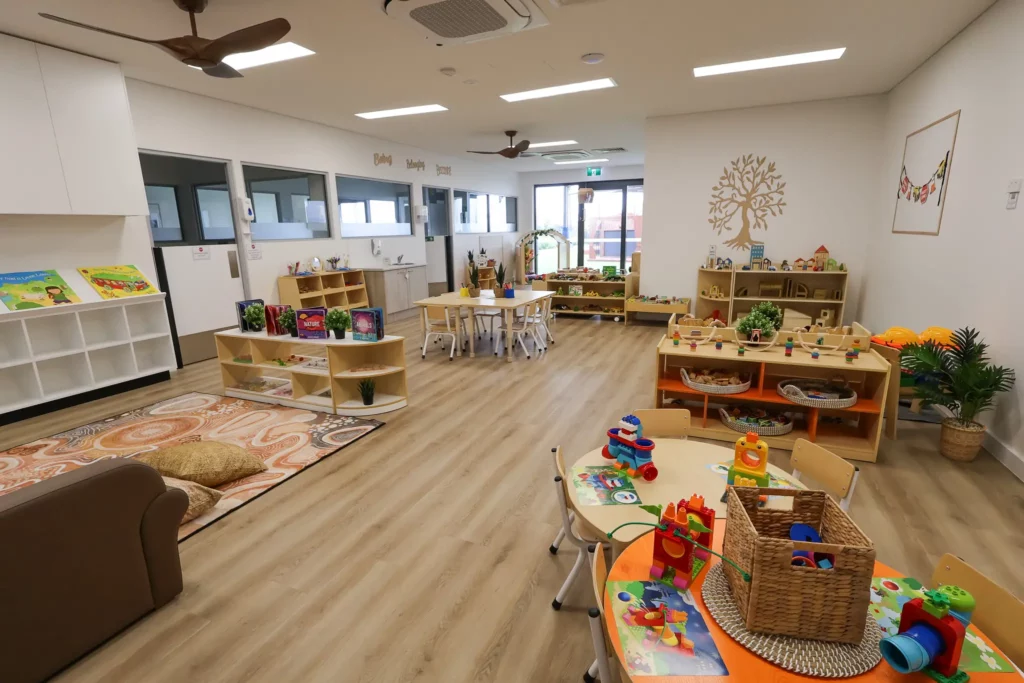 Indoor play area at Buttercups Perth Childcare with a natural aesthetic, featuring wooden elements and distinct sections designed for play, eating, and reading, creating a warm and inviting space for children to learn and engage in various activities.