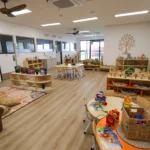 Indoor play area at Buttercups Perth Childcare with a natural aesthetic, featuring wooden elements and distinct sections designed for play, eating, and reading, creating a warm and inviting space for children to learn and engage in various activities.