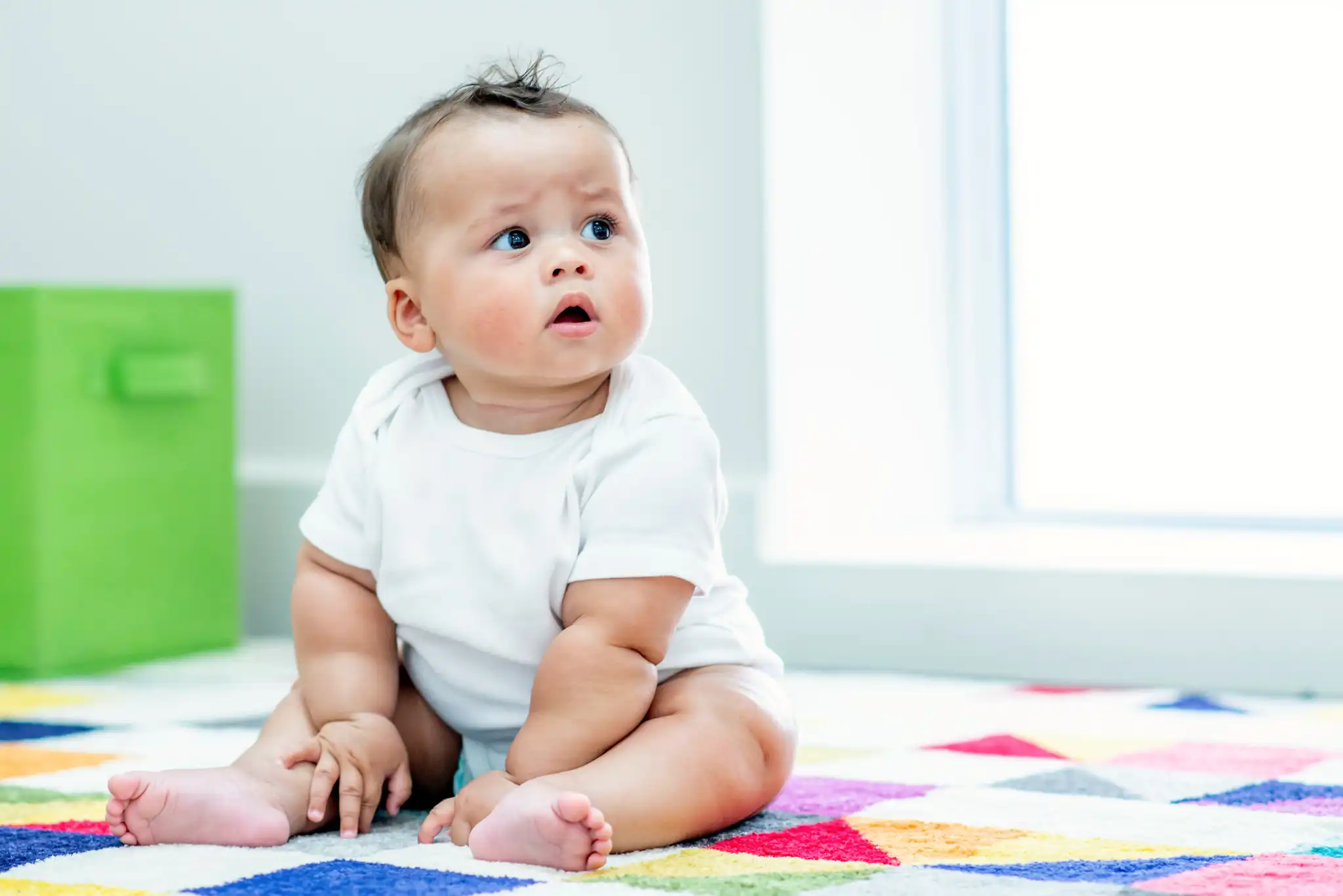 Baby sitting on a colourful rug at a Perth childcare centre, exploring a safe and nurturing space designed for early development.