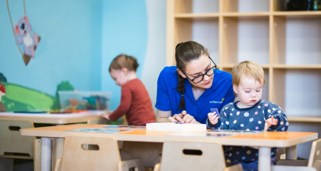Dedicated educator thoughtfully guiding a child through a puzzle at Buttercups Perth Childcare, fostering curiosity and learning.