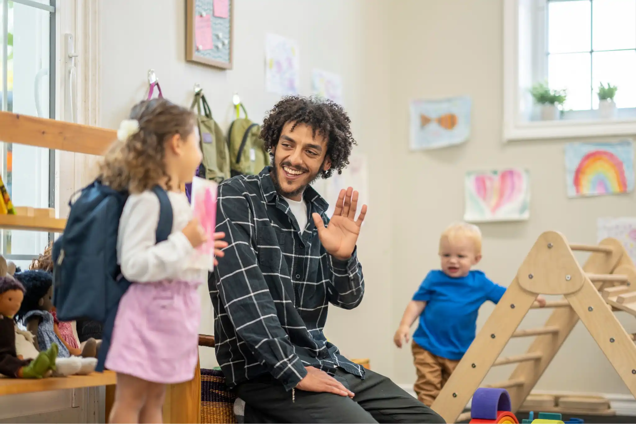 Educator greeting a child with a warm smile at a Perth daycare, creating a welcoming and inclusive environment for early learning and play.