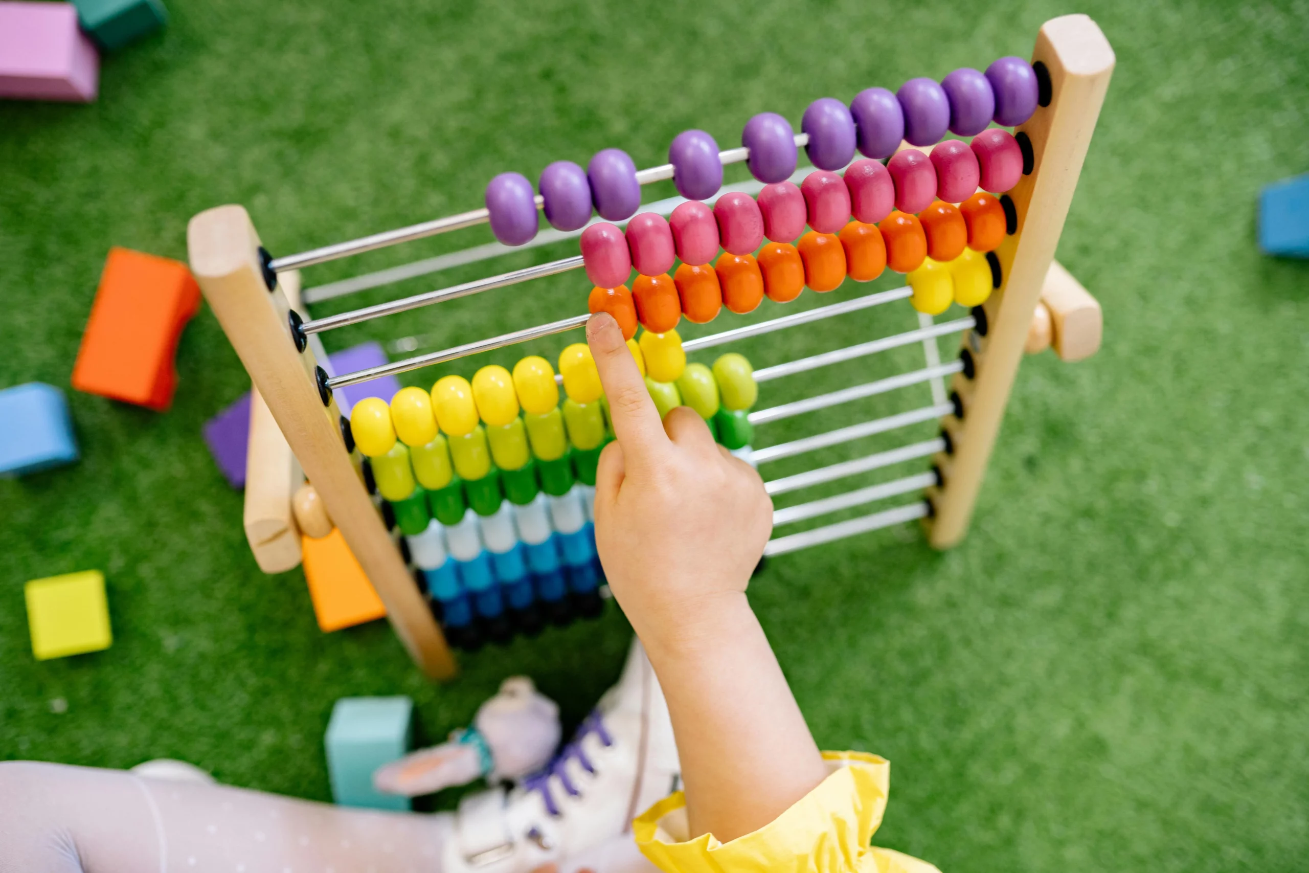 Child engaging with a colourful abacus at a Perth childcare centre, fostering early learning and development through play-based activities.