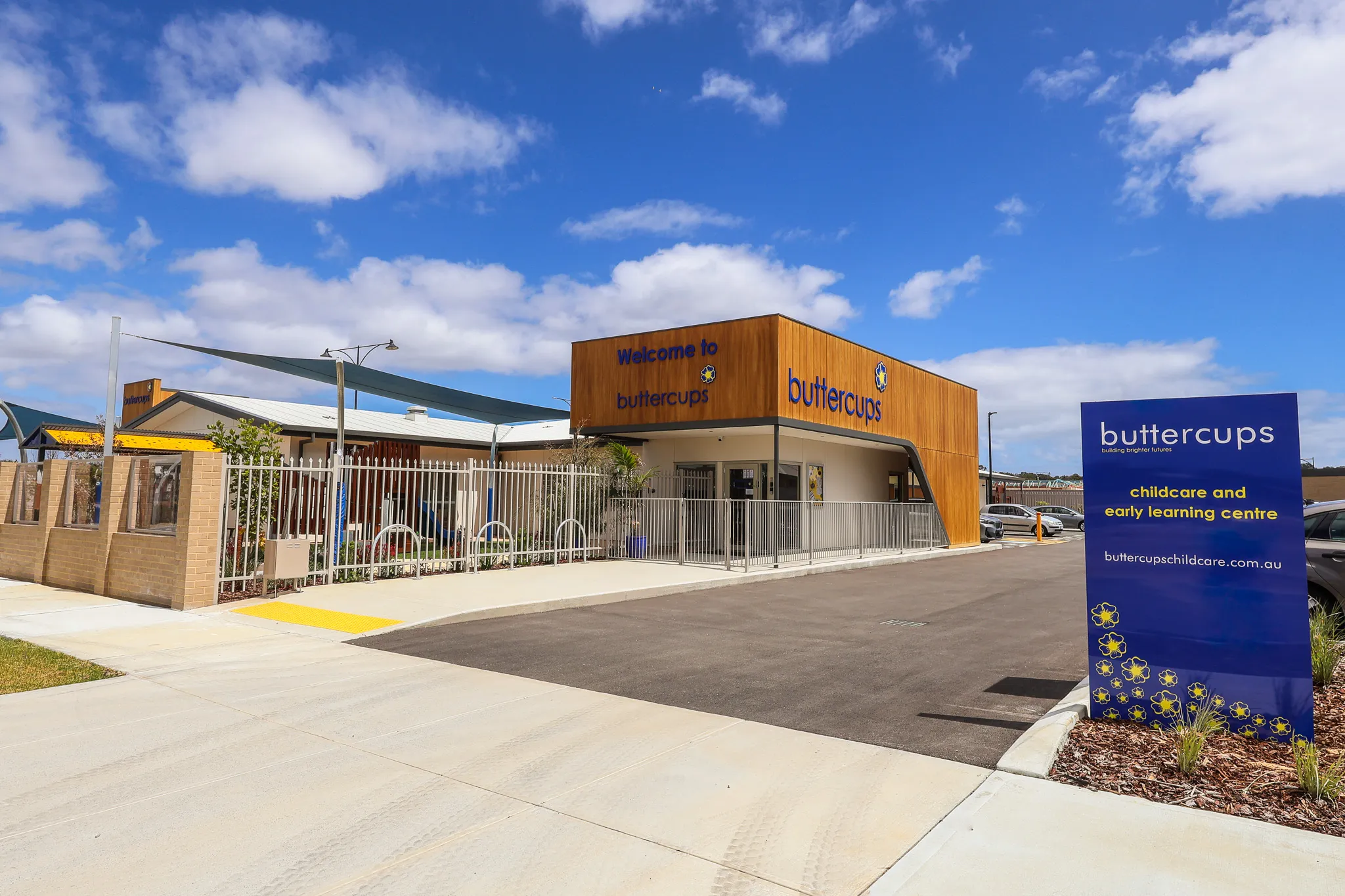 Buttercups Wellard Early Learning Centre as seen from the road, featuring a secure entryway and soft landscaping. A paved footpath and pram-friendly access points highlight the welcoming, purpose-built layout for families.