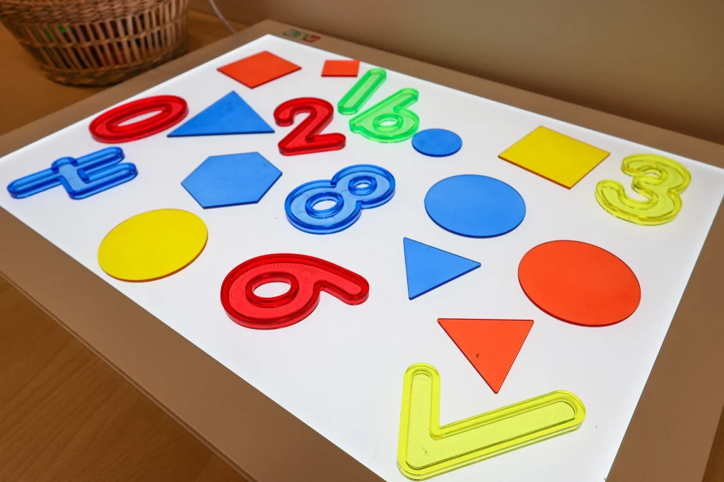 A light box at Buttercups Childcare displays colourful numbers and shapes for children to explore. The glowing surface encourages play-based learning, creativity, and sensory discovery.