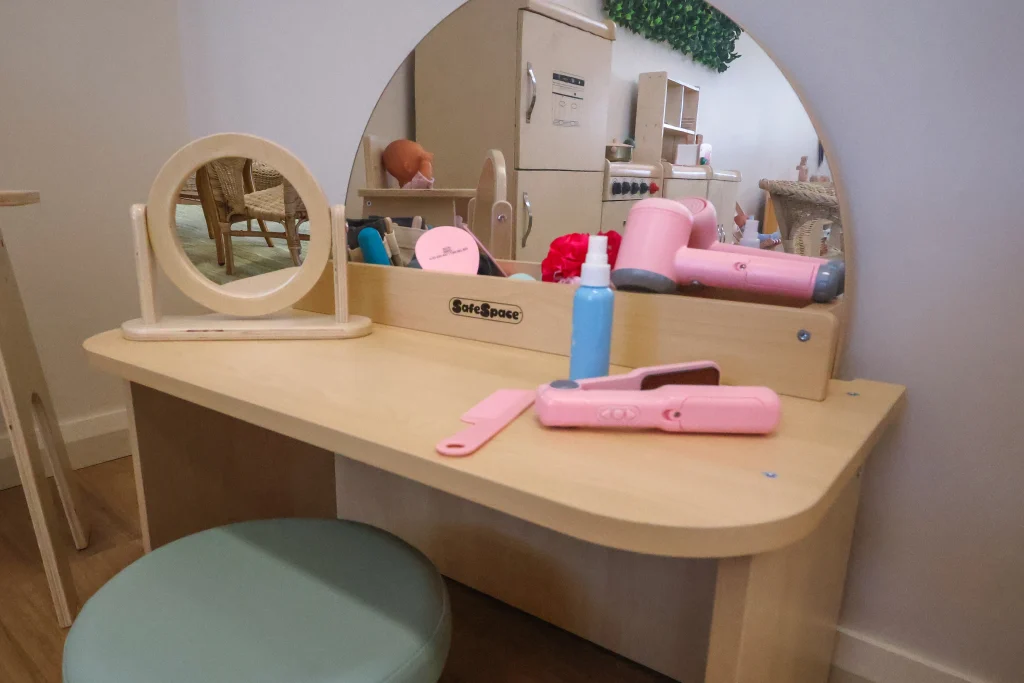 A home corner at Buttercups Childcare and Early Learning Centre Lakelands includes a child-sized vanity with mirrors and play accessories for imaginative role play. This engaging setup supports social development and self-expression through pretend play.