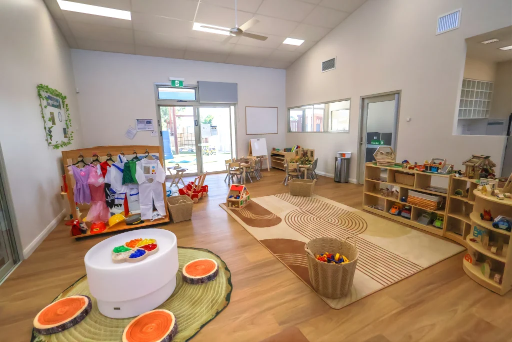The indoor learning environment at Buttercups Childcare and Early Learning Centre Lakelands features a dramatic play area with dress-ups, low shelving, and activity stations. Natural materials and open space encourage creativity and social development.
