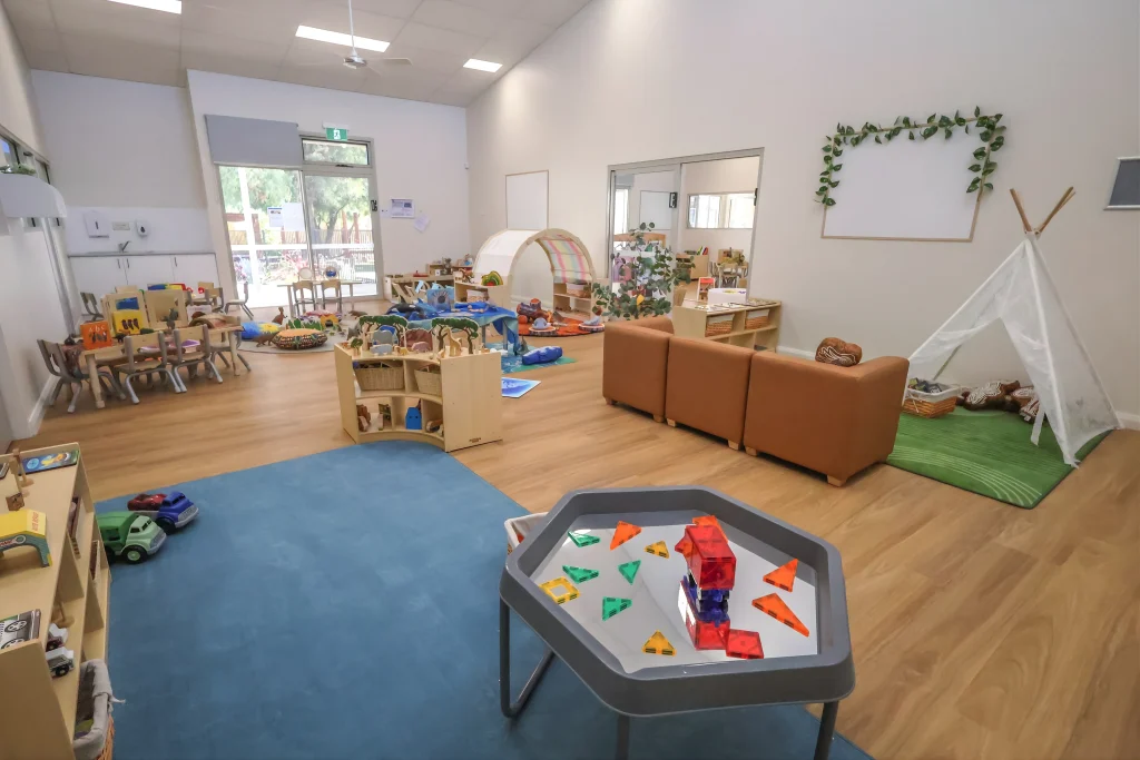 An open indoor learning space at Buttercups Childcare and Early Learning Centre Lakelands includes defined play areas with soft furnishings, activity tables, and a teepee reading nook. The layout encourages independent exploration and collaborative play.